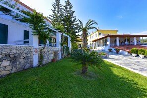 A courtyard with a stone wall, a palm tree, and a building with a tiled roof and a balcony.