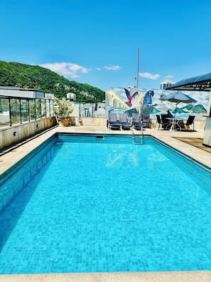 Una piscina al aire libre, sillones reclinables de piscina