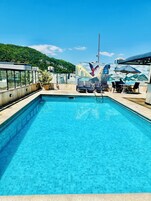 Una piscina al aire libre, sillones reclinables de piscina