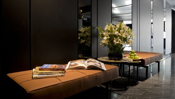Un hall d’entrée moderne avec un banc en cuir, une table ornée d’un vase de fleurs et un livre.