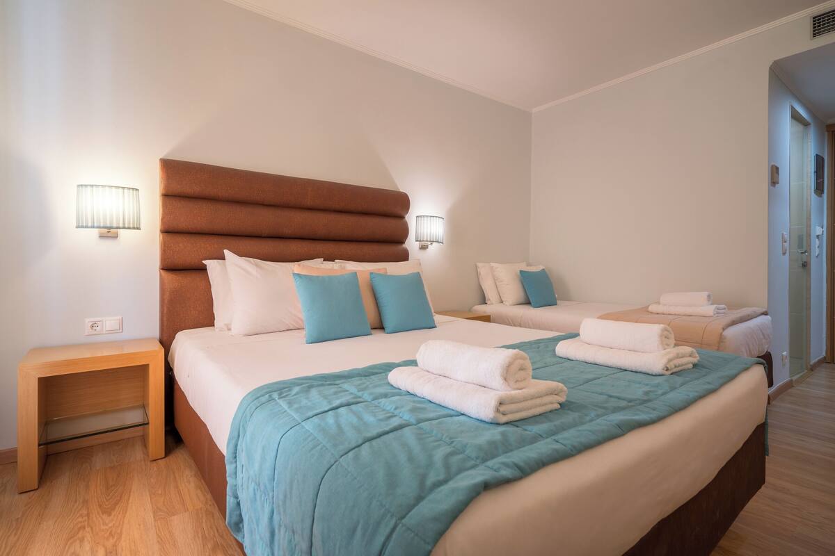 A hotel room with two beds, each with a headboard, a nightstand, and a wall-mounted lamp.