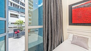 Een moderne hotelkamer met balkon, groot raam en een schilderij aan de muur.