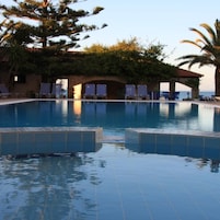 A swimming pool with lounge chairs and a view of the sea.