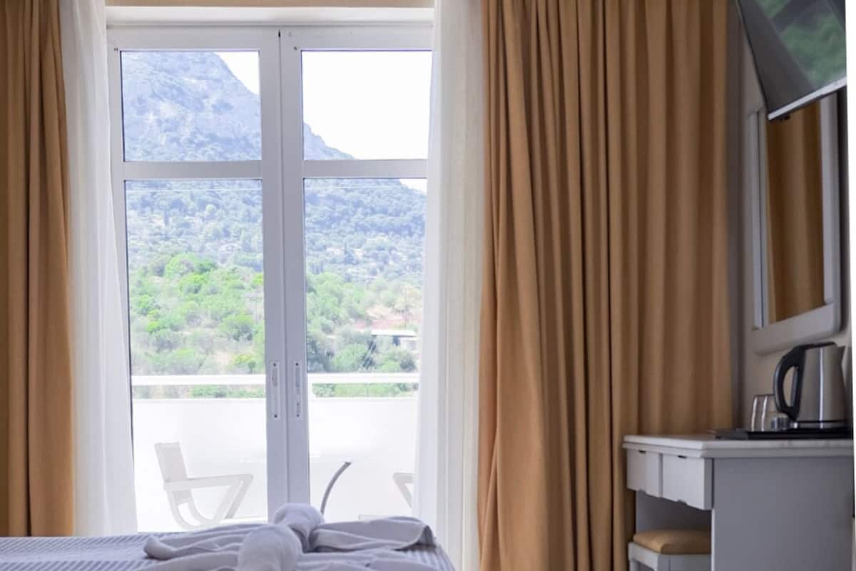 A hotel room with a bed, a desk, a chair, a television, and a view of the outdoors.