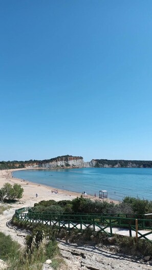 A beach with clear blue water, sandy shore, and a rocky cliff in the background. - Matilda Hotel by Anayia All Inclusive Resorts (Zakynthos)