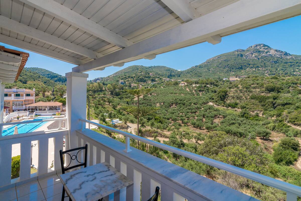 A balcony with a view of a mountainous landscape and a pool area.