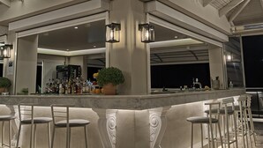 A bar area with a high ceiling, bar stools, and a well-stocked bar counter. - Matilda Hotel by Anayia All Inclusive Resorts (Zakynthos)