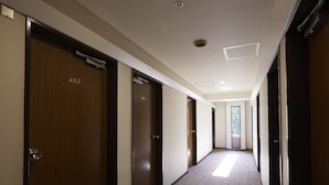 Un pasillo de hotel con puertas de madera, pisos alfombrados e iluminación empotrada.