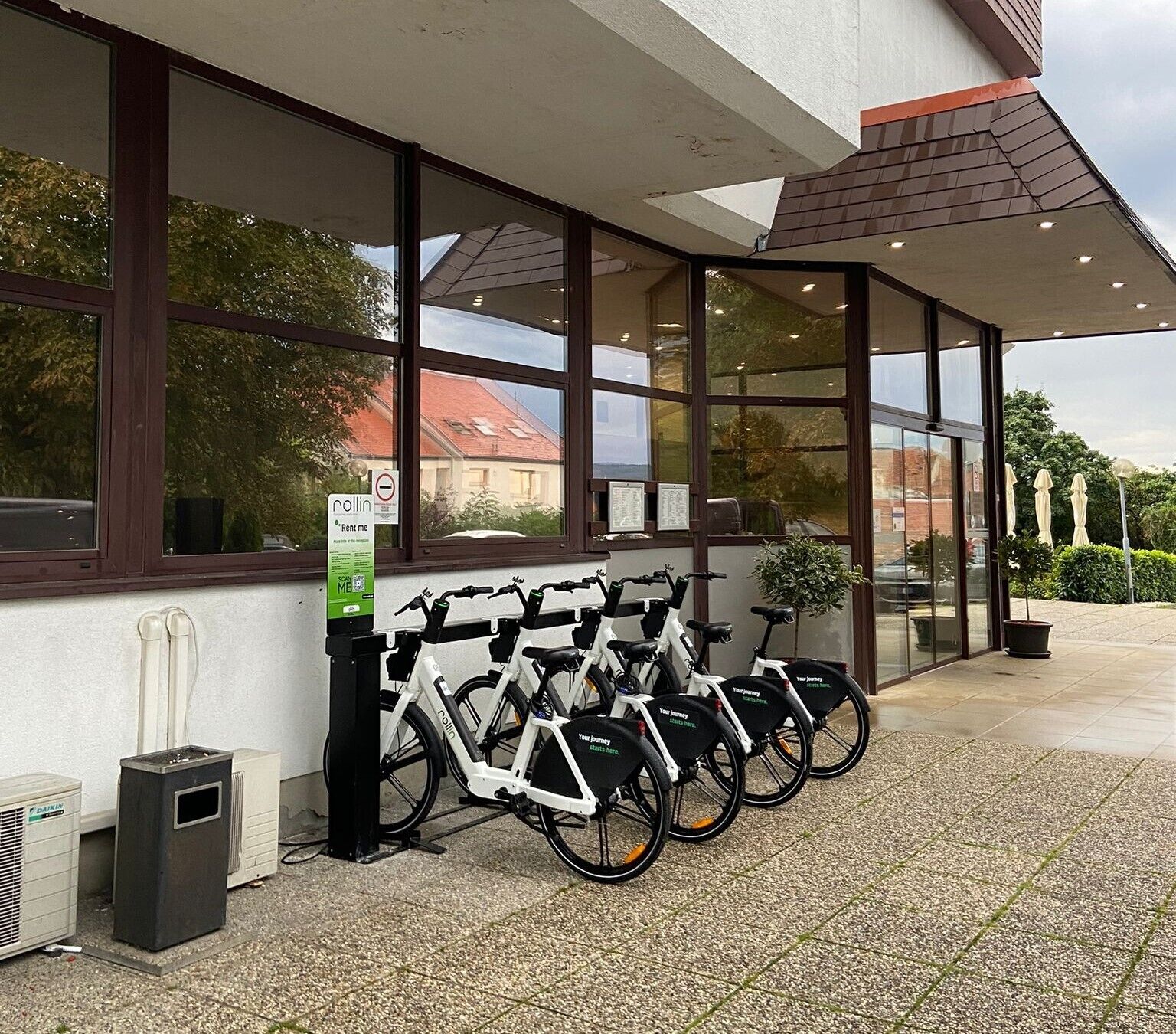 A building with large windows, a bike rental station, and a sign for a rental service.