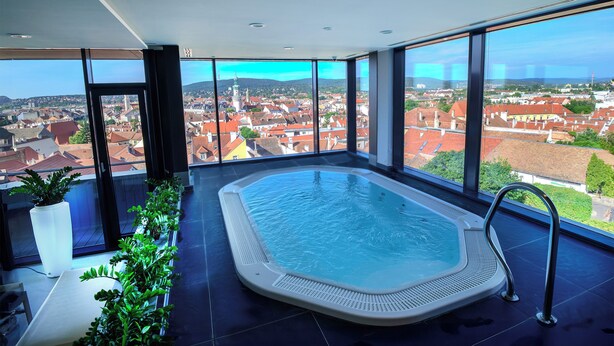 A modern indoor swimming pool with a panoramic city view. - Hotel Sopron (Sopron)