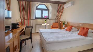 A hotel room with a bed, desk, chair, and a window with curtains.