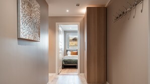 A hallway leading to a bedroom with a bed, a wooden panel, and a wall-mounted hookboard. - Ustedalen Hotell Geilo (Hol)