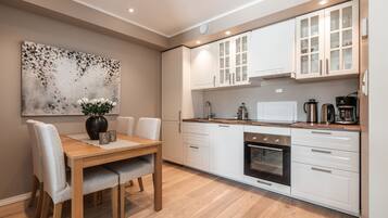 Una cocina moderna con armarios blancos, una mesa de comedor de madera y un cuadro en la pared.
