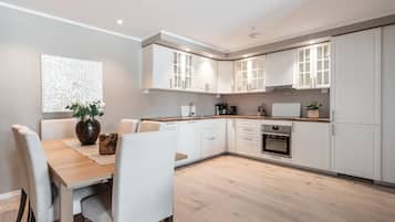 Una cocina moderna con armarios blancos, una mesa de comedor de madera y un jarrón con flores.