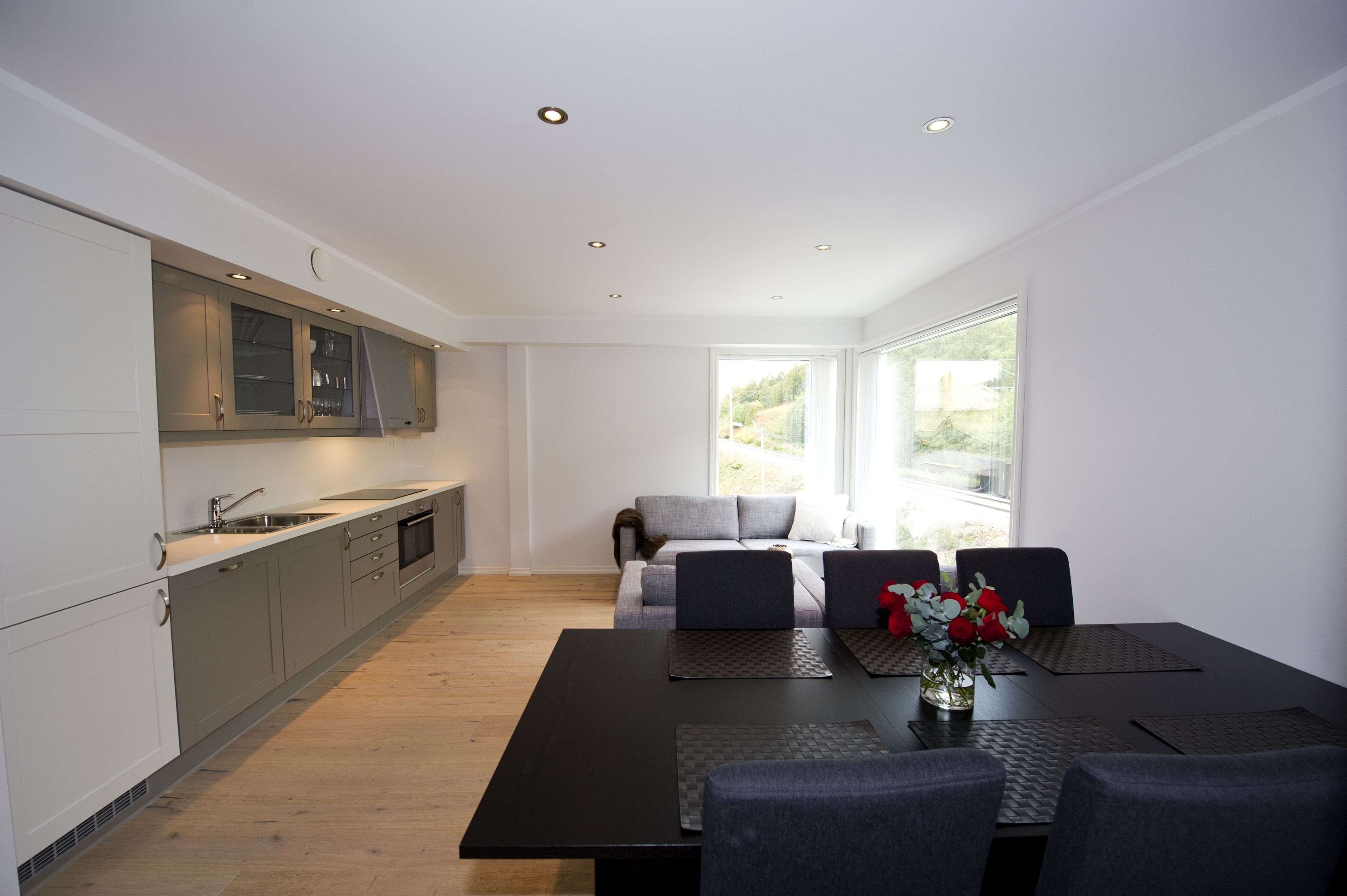 A modern kitchen with built-in appliances, a dining area with a table and chairs, and a sofa.