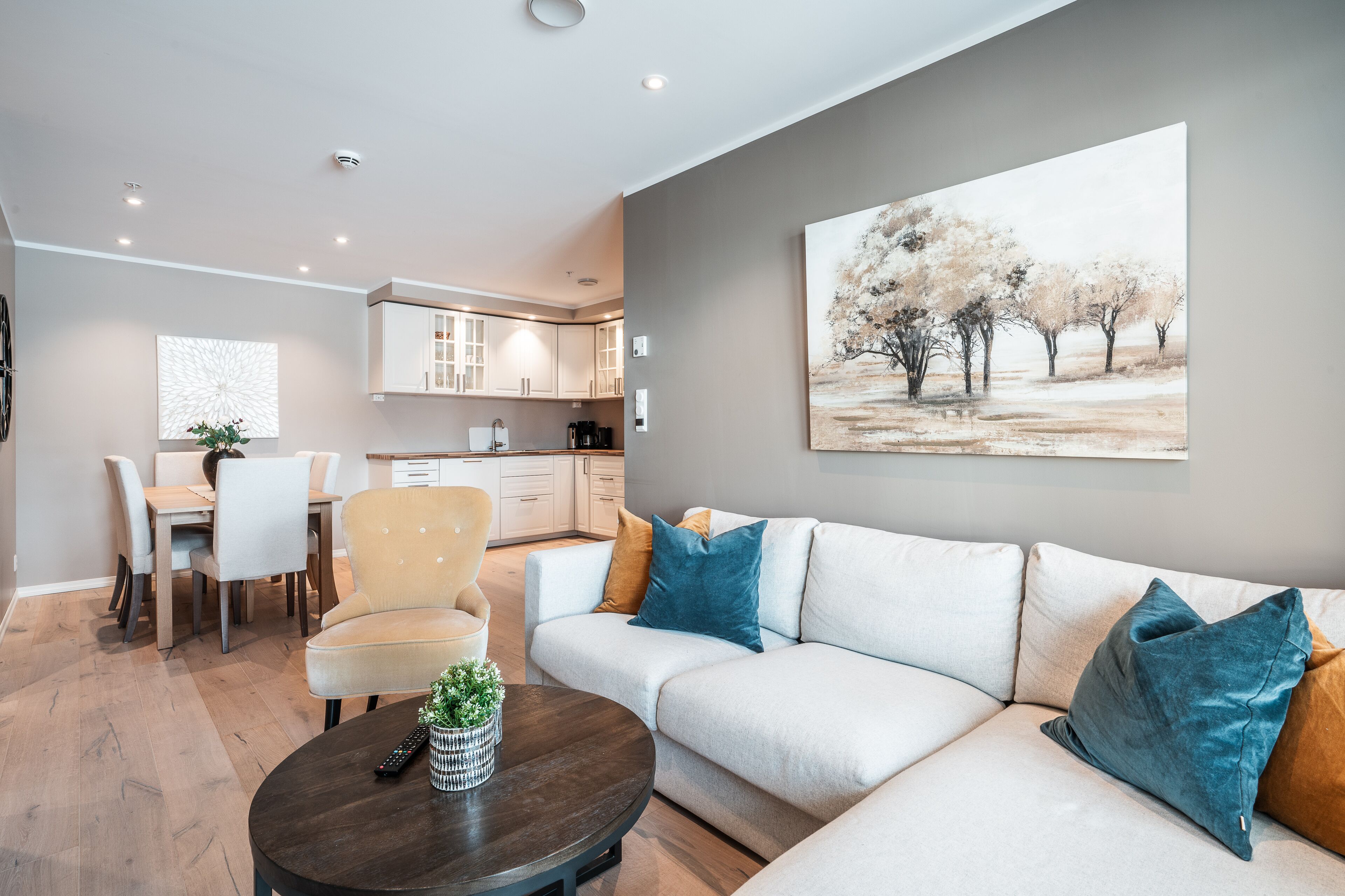 Een moderne woonkamer met een bank, een eettafel en een keuken op de achtergrond.