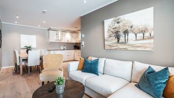 Een moderne woonkamer met een bank, een eettafel en een keuken op de achtergrond.