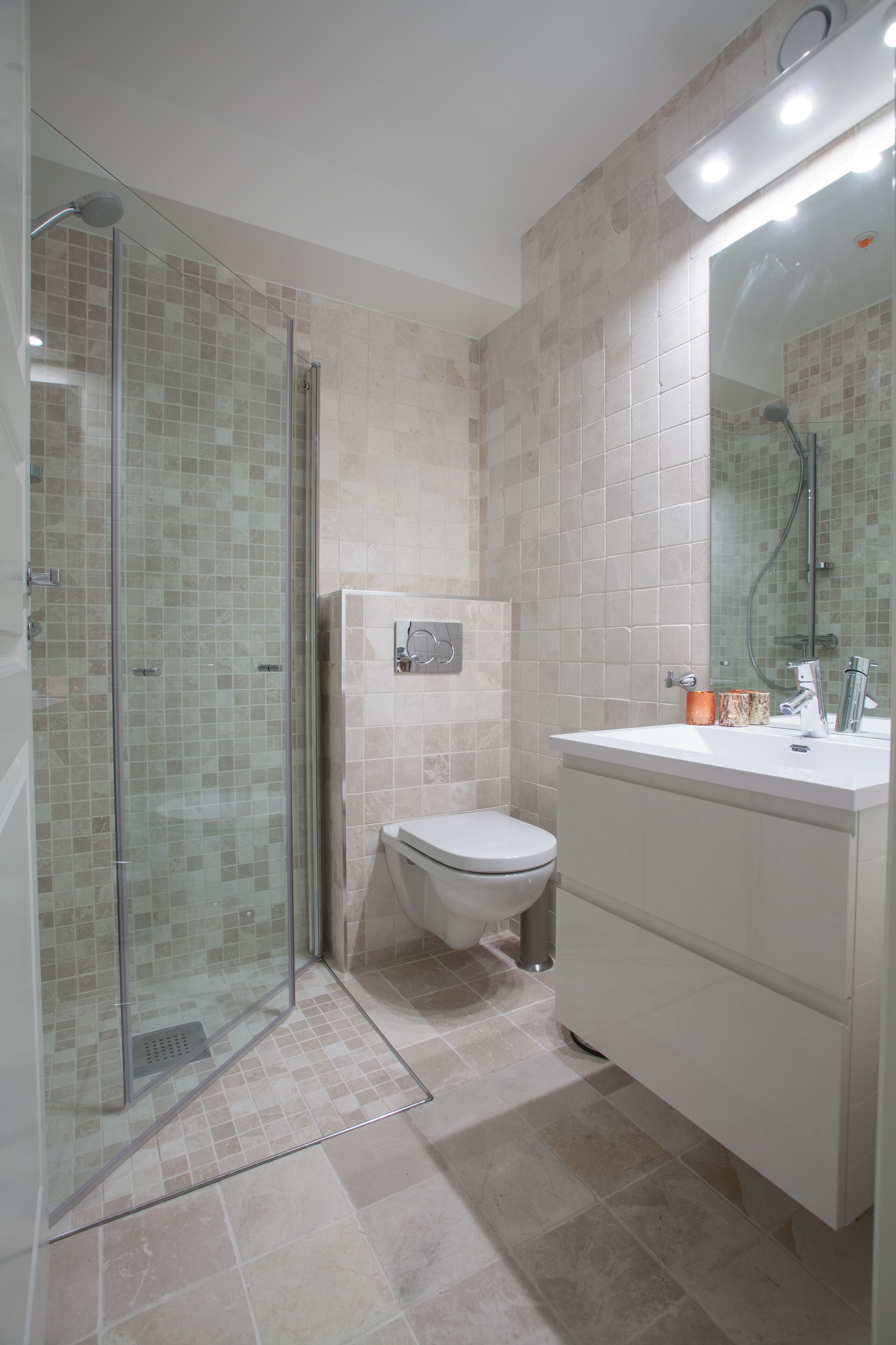 A modern bathroom with a glass-enclosed shower, a toilet, and a vanity with a mirror.