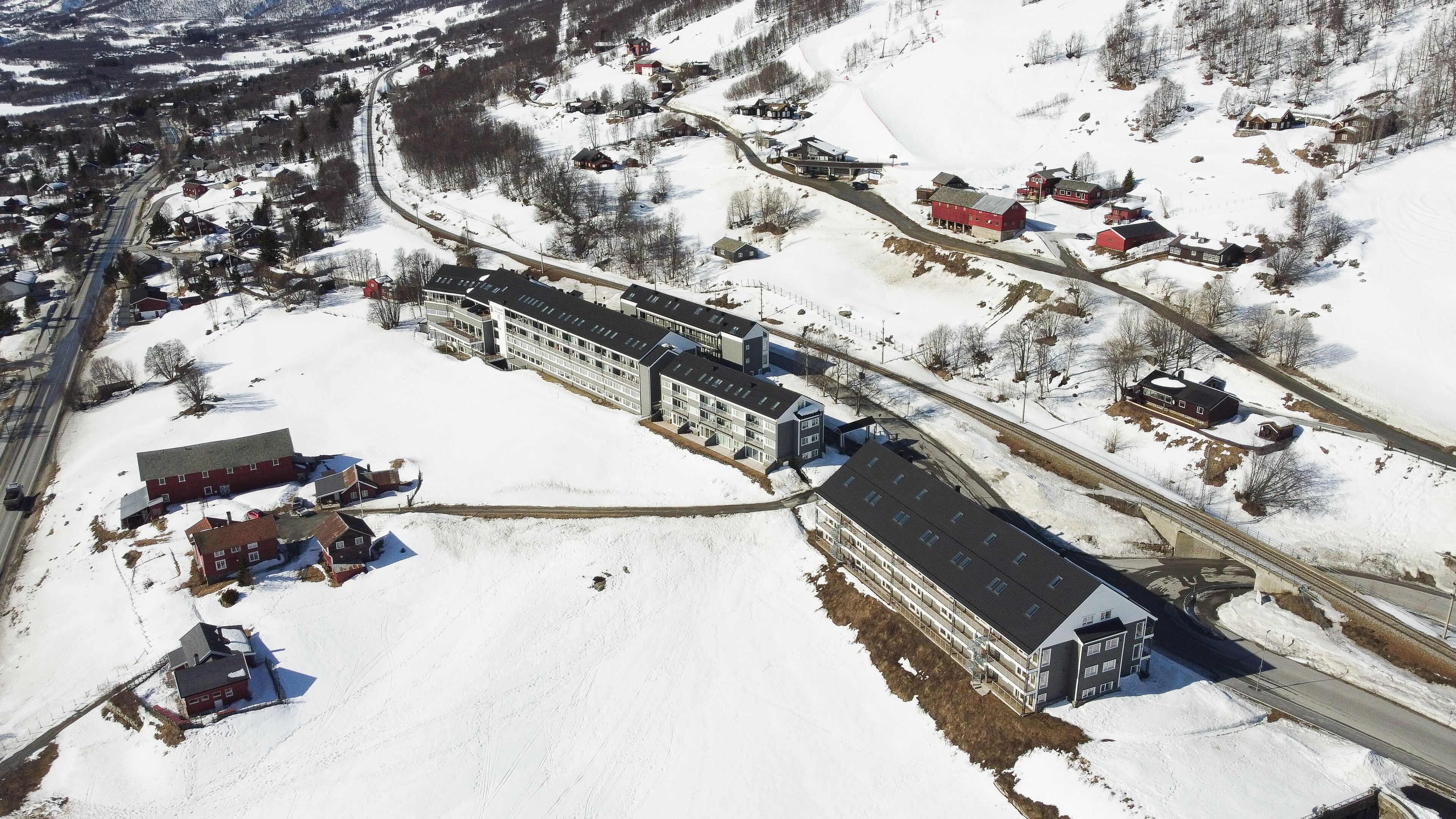 Un grand bâtiment à plusieurs étages, doté d’une cour intérieure, entouré d’un terrain enneigé et de quelques bâtiments plus petits.