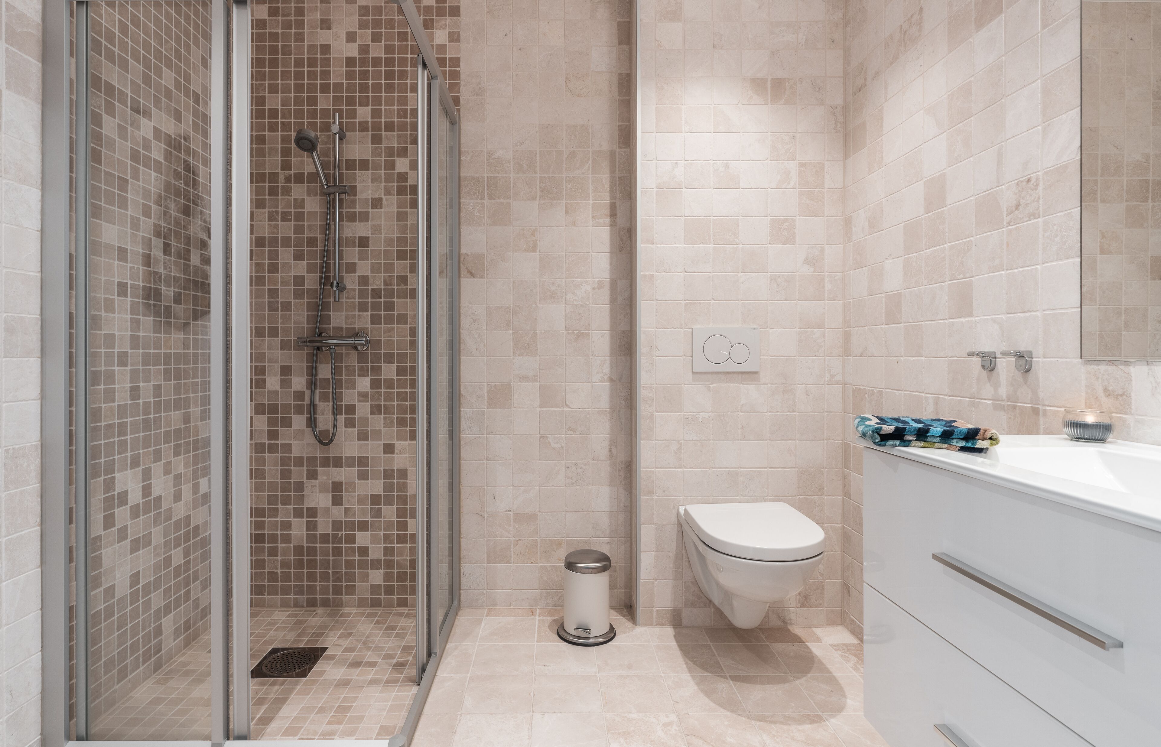 A modern bathroom with a glass-enclosed shower, a toilet, and a white sink with a mirror.