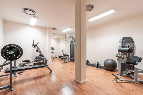 Un gimnasio con máquinas de cardio, equipo de levantamiento de pesas y una pelota de ejercicios grande.