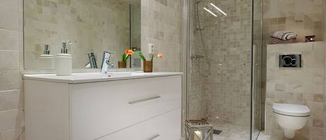 A modern bathroom with a glass-enclosed shower, a large mirror, and a white vanity.