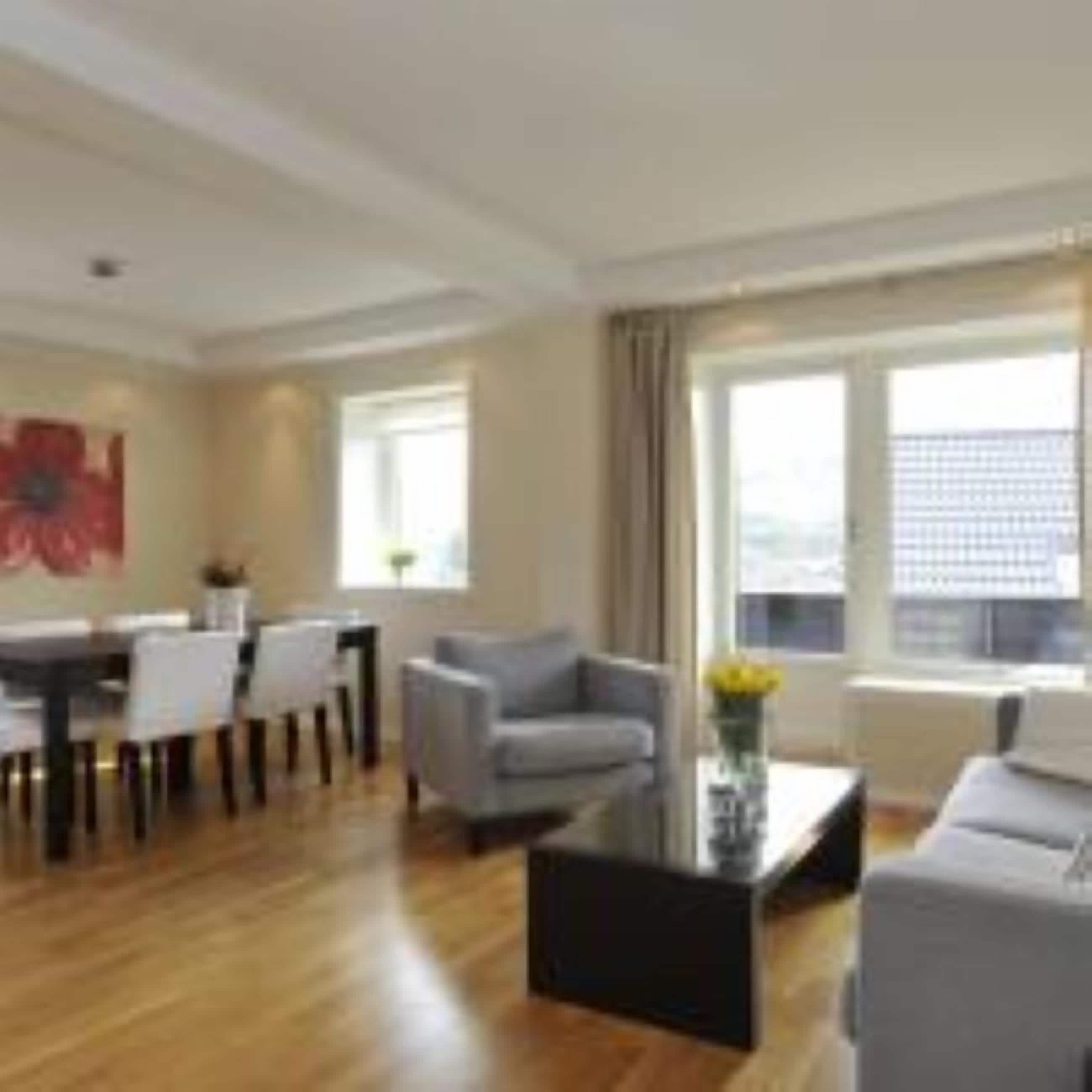 Ein modernes Wohnzimmer mit Essbereich, großen Fenstern und Blick auf die Stadt.