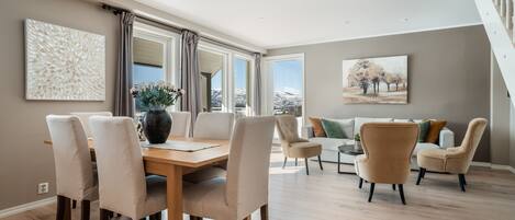 Amplia sala de estar con mesa de comedor de madera, sillas color beige y un juego de sofás.