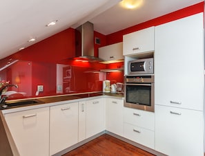 A modern kitchen with white cabinets, a stainless steel oven, and a microwave.