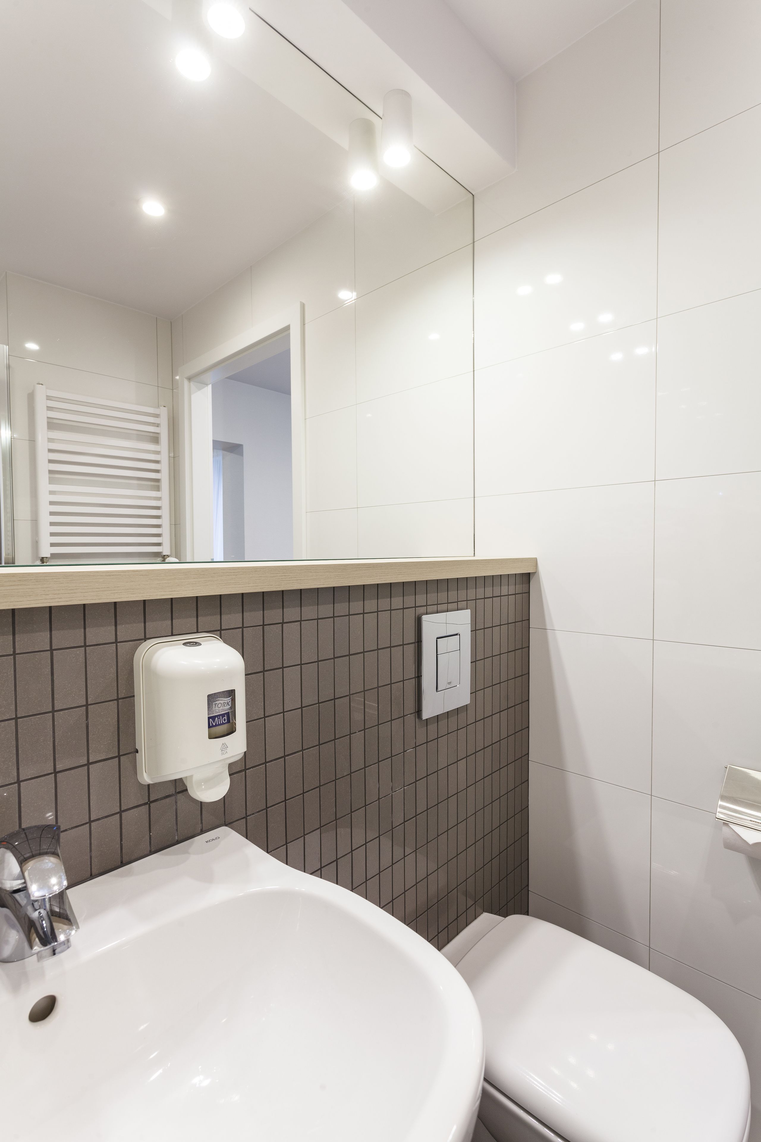 Ein Badezimmer mit einem weißen Waschbecken, einer Toilette und einem Spiegel über dem Waschbecken.