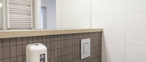 Ein Badezimmer mit einem weißen Waschbecken, einer Toilette und einem Spiegel über dem Waschbecken.