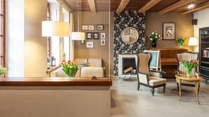 A cozy living room with a fireplace, comfortable seating, and a bookshelf. - Hotel Czarna Róża (Torun)
