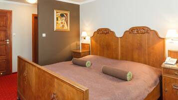 A wooden bed with a headboard, two bedside tables, and a wall-mounted lamp.