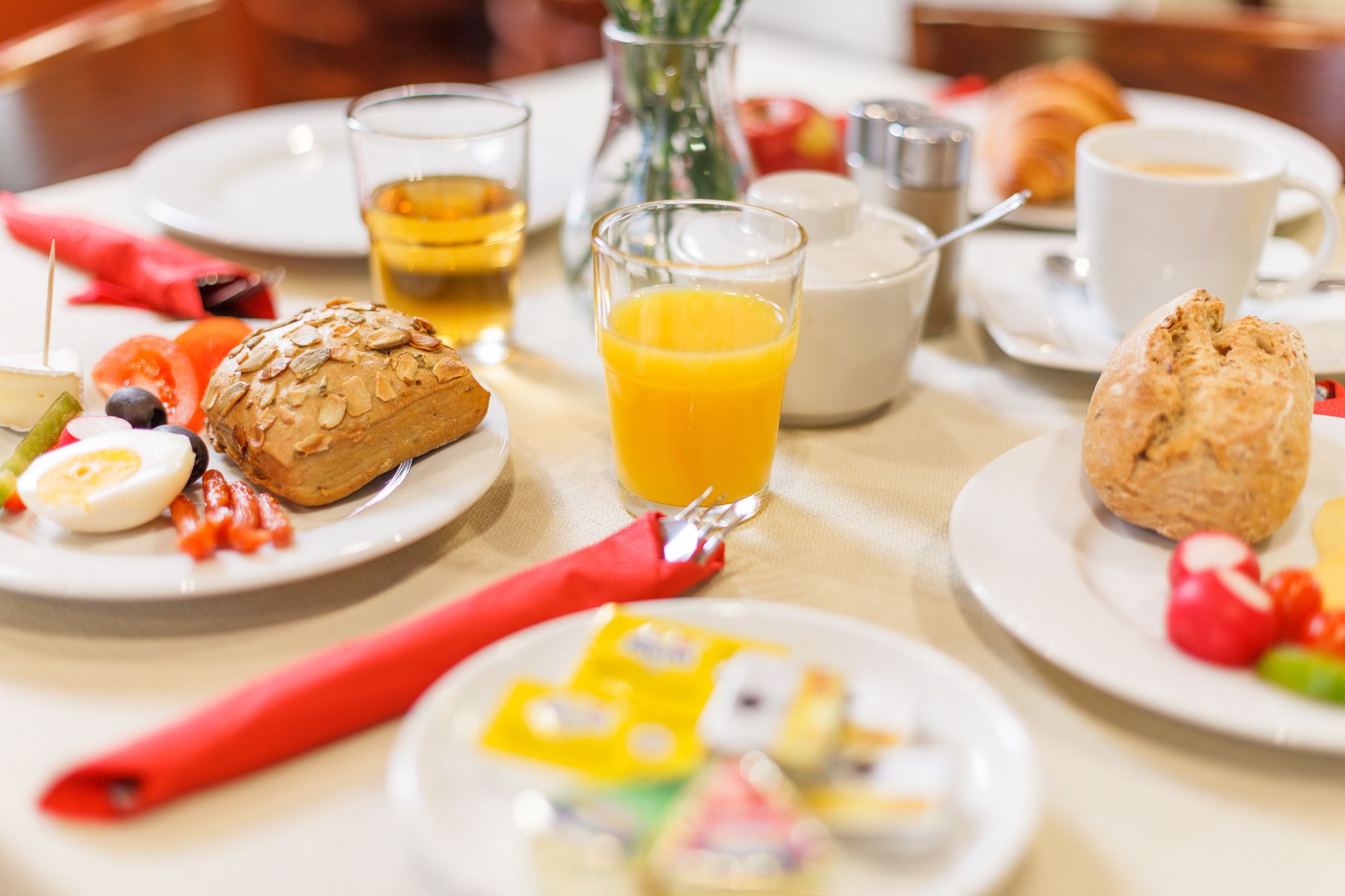 A breakfast setting with plates of food, including toast, eggs, and vegetables, along with glasses of orange juice and coffee.