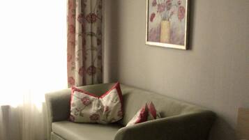 A room with a bed, a sofa, and a painting on the wall.