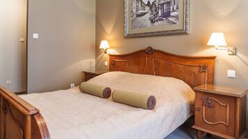 A neatly made bed with a wooden headboard, two bedside lamps, and a framed picture on the wall.