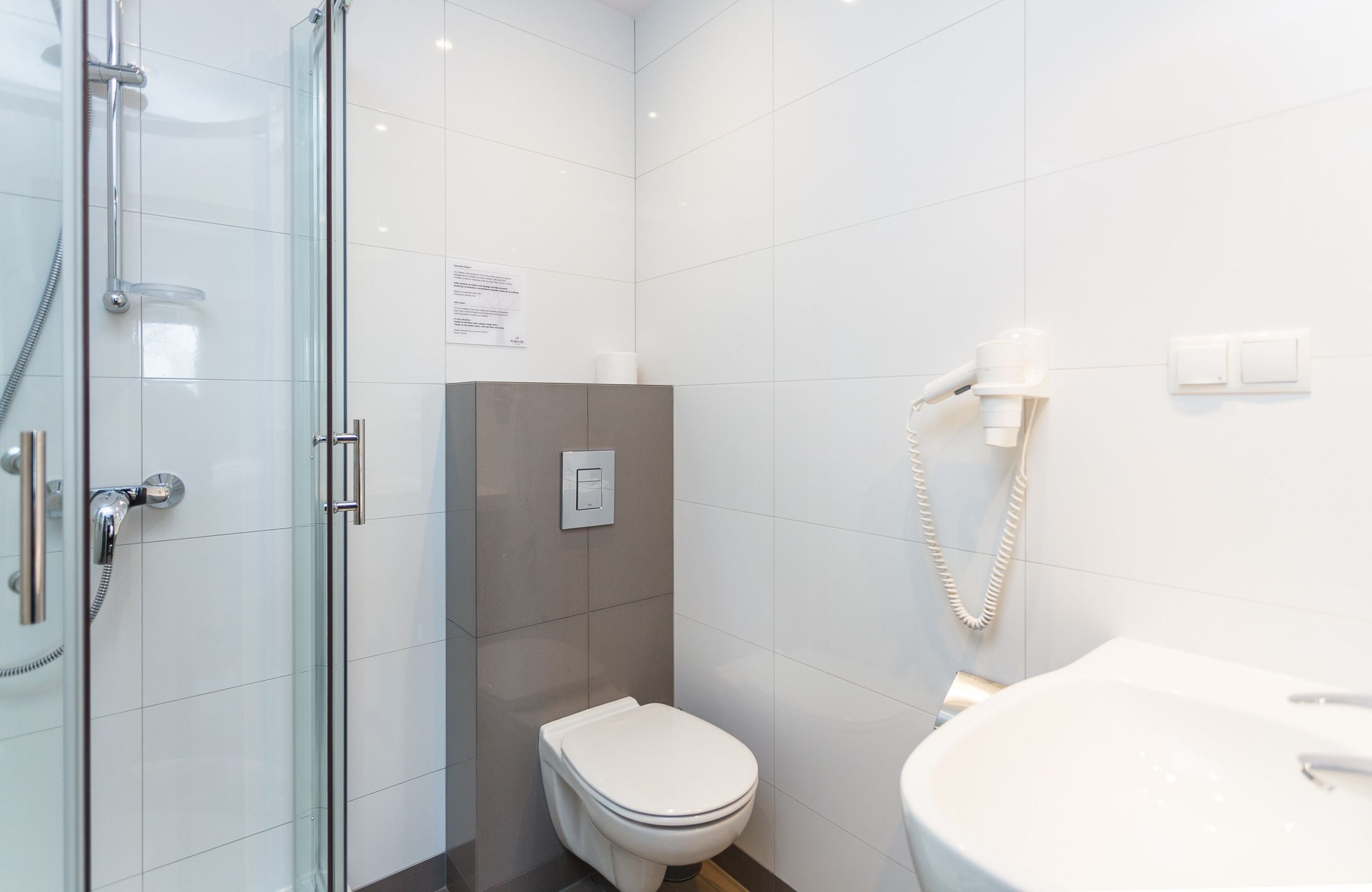 Un baño moderno con cabina de ducha de vidrio, inodoro y lavamanos.