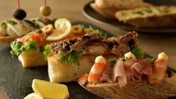 A variety of appetizers on a slate board, including bread with toppings and garnishes.