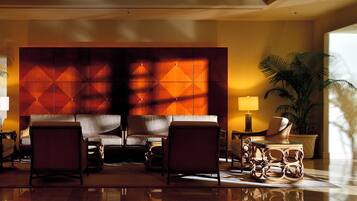 A lobby with a large seating area, a decorative wall, and a potted plant.