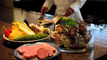 A kitchen counter with various food items including vegetables, a bowl of seafood, and a plate of meat.