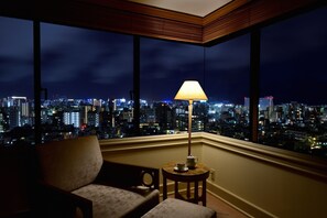 A room with a view of a cityscape at night, a lamp, and a chair. - The Naha Terrace (Naha)