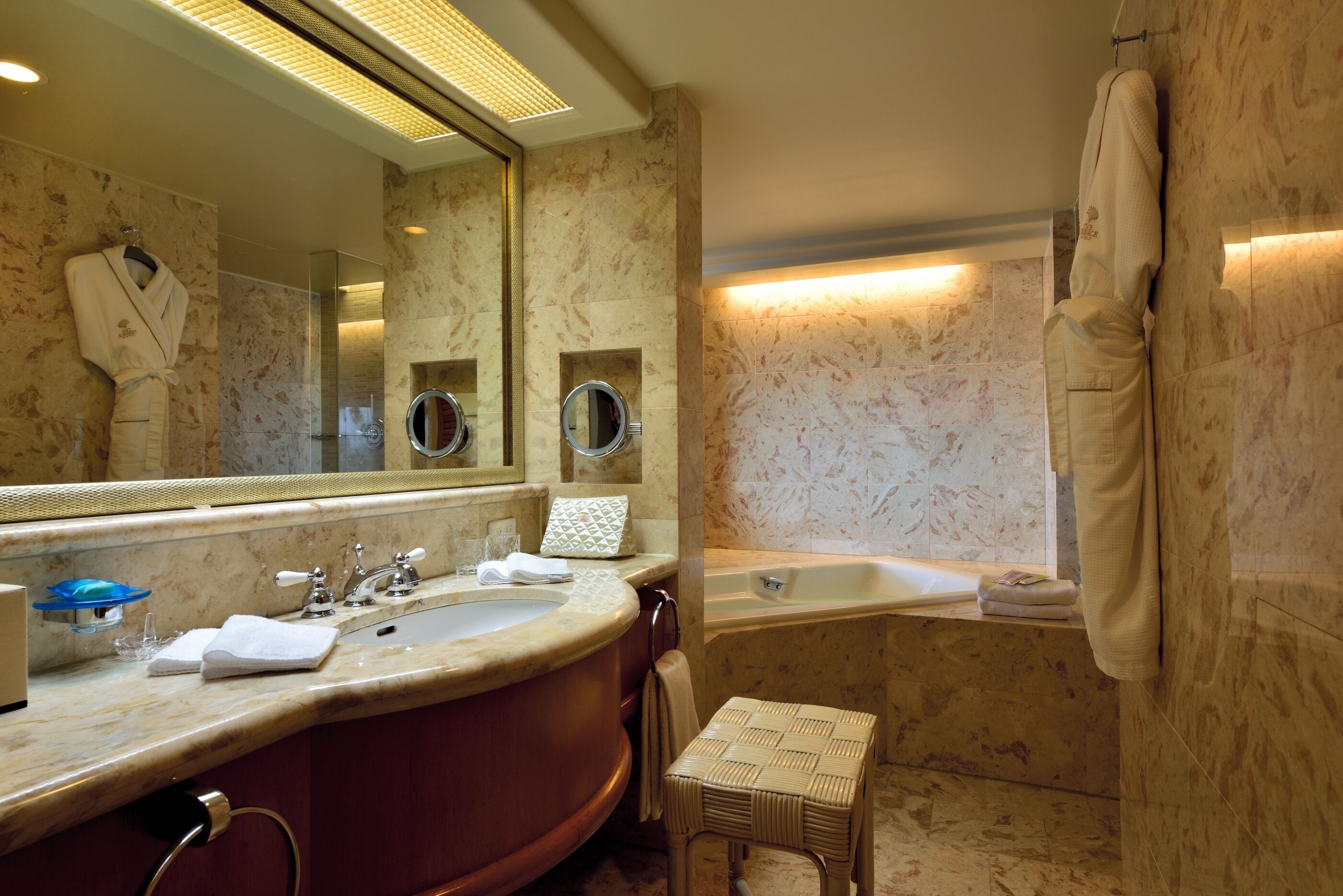 A bathroom with a large mirror, a bathtub, a vanity with a sink, and a towel rack.