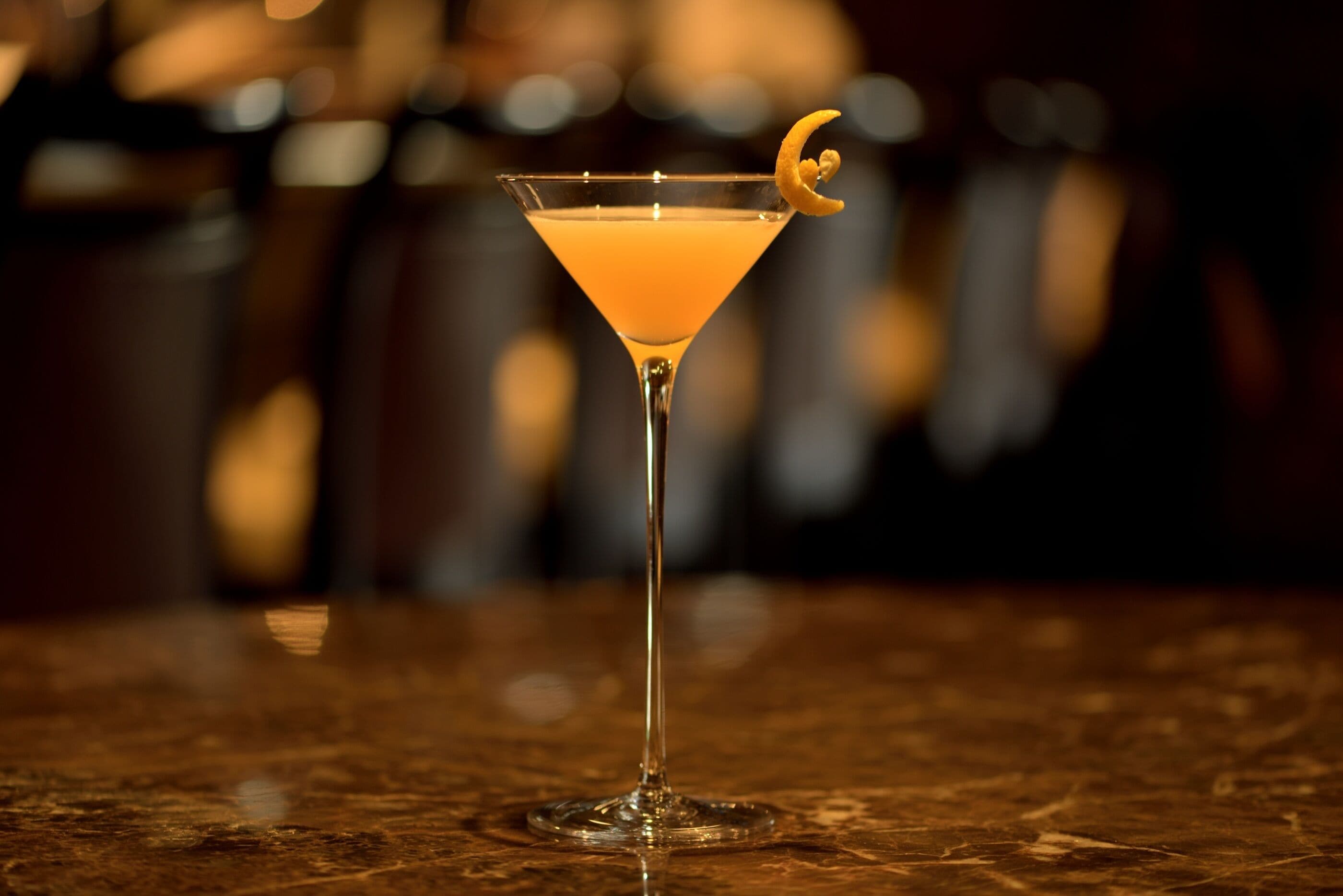 Una copa de martini con una rodaja de limón sobre una superficie de mármol.