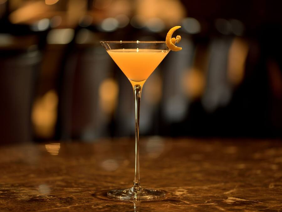 Una copa de martini con una rodaja de limón sobre una superficie de mármol.