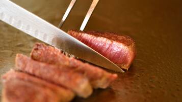 A knife cutting through a piece of meat on a cutting board.