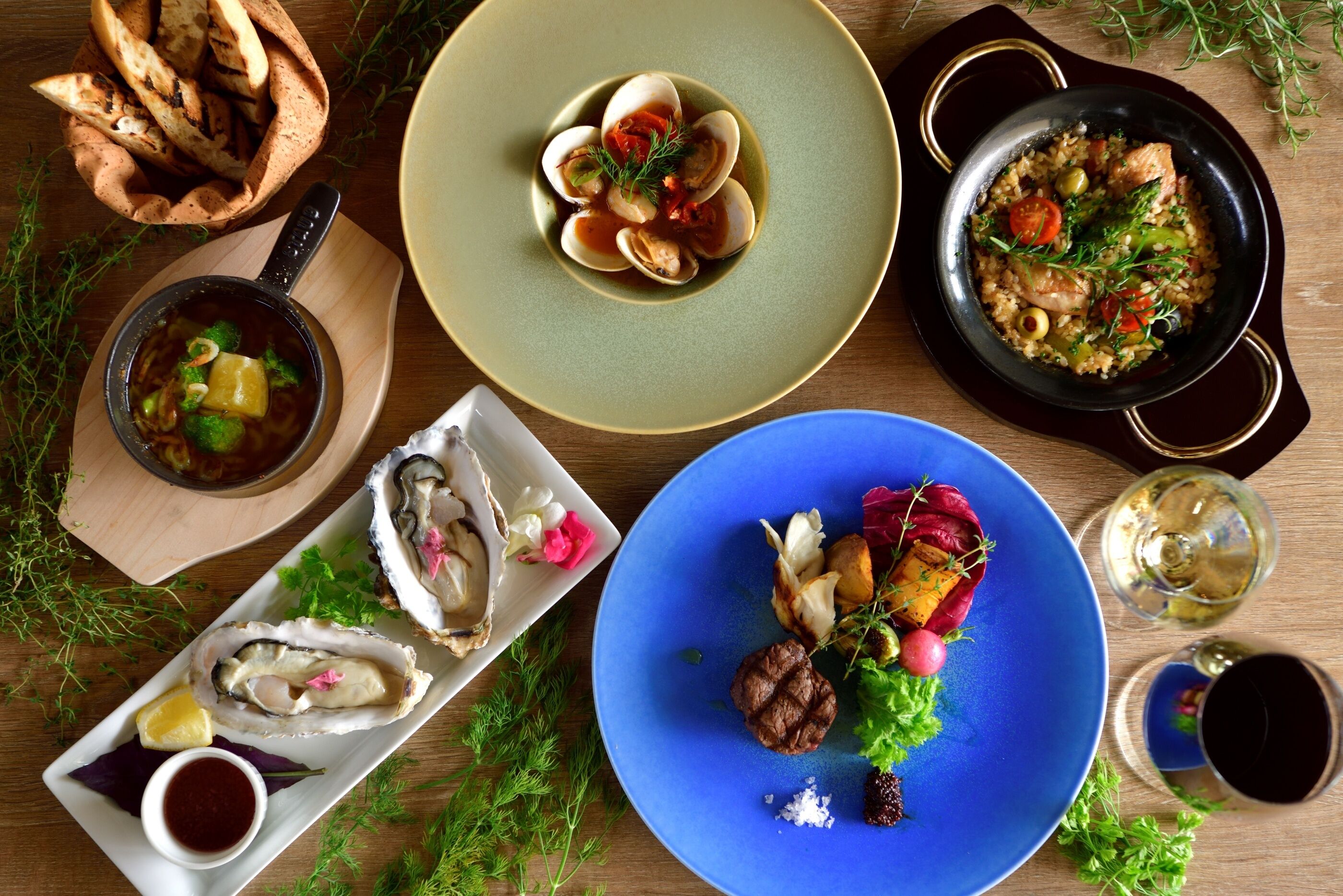 A variety of dishes including seafood, vegetables, and a blue plate with a meat dish, suggesting a diverse meal selection.