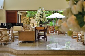 A spacious indoor area with a piano, comfortable seating, and a table with a floral arrangement. - The Naha Terrace (Naha)