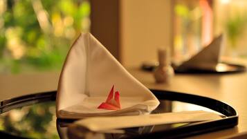 A tray with a folded napkin and a red origami crane on a reflective surface.