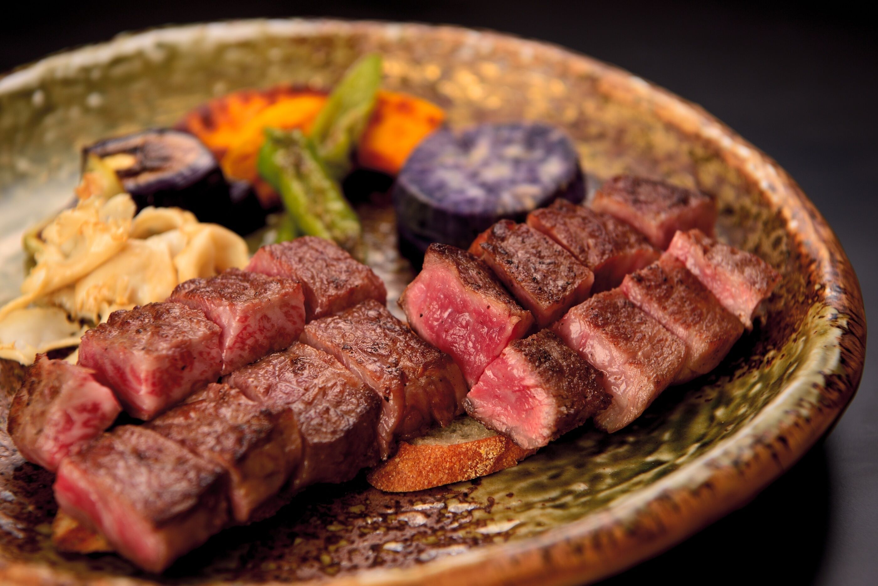 A plate of sliced steak with vegetables.