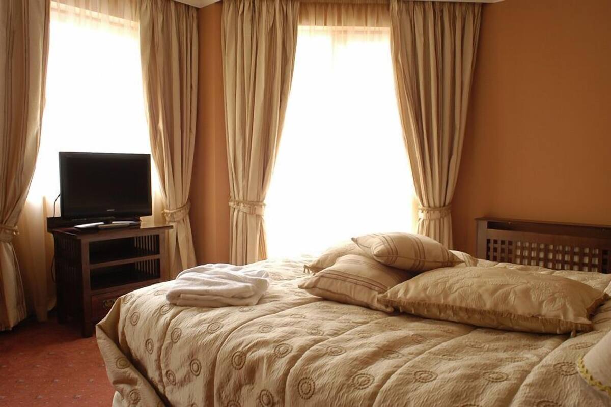 A hotel room with a bed, a television on a stand, and curtains.